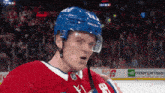 a hockey player wearing a blue helmet stands on the ice in front of an enterprise ad