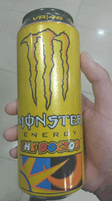 a hand holds a yellow can of monster energy the doctor