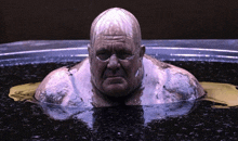 a bald man with glasses is swimming in a tub