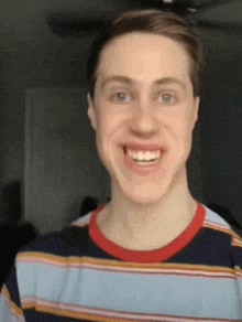 a young man in a striped shirt smiles for the camera