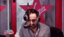 a man wearing headphones is sitting in front of a microphone .