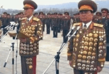 two men in military uniforms are standing in front of microphones .