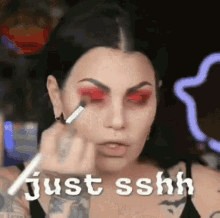 a woman is applying red eye shadow to her eyes .