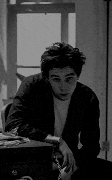 a black and white photo of a young man sitting at a desk .