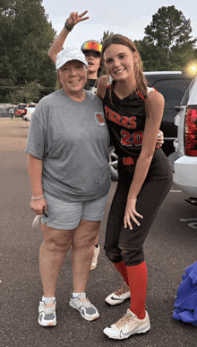 a girl in a tigers jersey stands next to a woman in a grey shirt