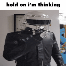 a man wearing a helmet and a leather jacket is standing in front of a wall .