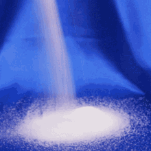 white powder is being poured into a blue container