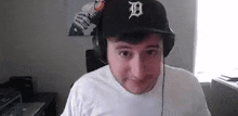 a man wearing headphones and a baseball cap is sitting in front of a computer .