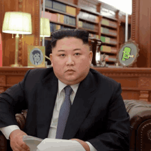 a man in a suit and tie is sitting on a couch in front of a bookshelf