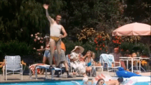 a man in a bathing suit is jumping into a swimming pool