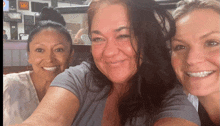 three women are posing for a picture and one of them has a sign on the wall that says ' texas ' on it