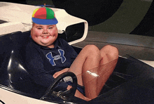 a boy wearing a blue under armour sweatshirt sits in a car