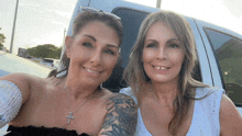 two women are posing for a picture in front of a white van