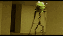 a green kermit the frog is hanging from a rope