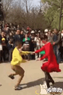 a man in a yellow shirt and a woman in a red dress are dancing in front of a crowd of people ..