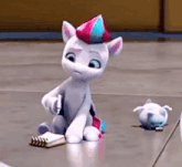a white cartoon pony is sitting on the floor next to a notebook and a smaller pony .