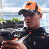 a man wearing an orange mclaren hat looks at his cell phone