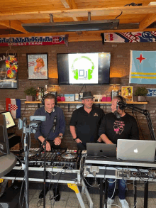 a group of men are playing music in front of a screen that says dj on it