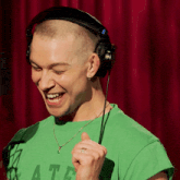 a man wearing headphones and a green shirt that says ate is smiling
