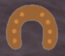 a brown horseshoe with orange dots on a dark background