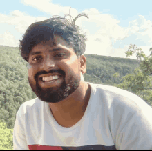 a man with a beard wearing a white shirt is smiling