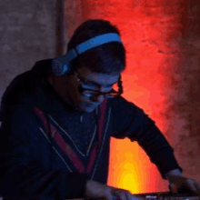 a man wearing headphones and glasses is playing music on a dj controller .