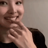 a close up of a woman 's face with her hand on her chin and a ring on her finger .