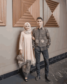 a man and a woman standing next to each other in front of a wooden wall