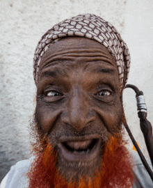 a man with a red beard wearing a head scarf looks at the camera