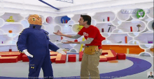 a man in a red shirt is standing next to a robot