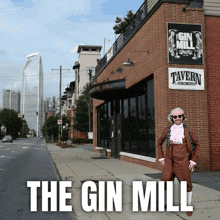 a man standing in front of a building that says the gin mill tavern