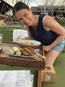 a woman leans over a wooden tray with a plate of food