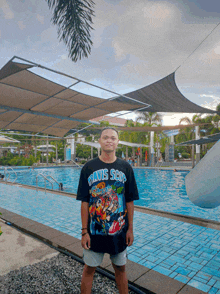 a man wearing a davis scott t-shirt stands in front of a pool