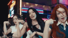 a group of young women are dancing in front of a neon sign in a city .