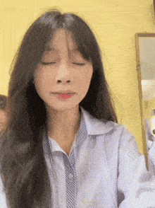 a girl with her eyes closed is wearing a blue and white shirt