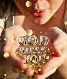 a woman is blowing gold confetti out of her hands with the words god bless you written on it .