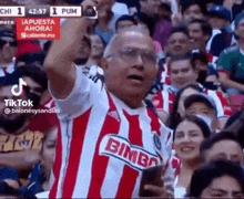 a man in a red and white striped shirt is standing in front of a crowd of people .