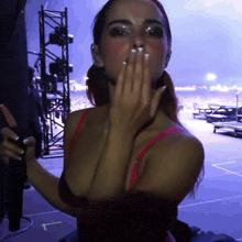 a woman in a red bra is blowing a kiss with a purple background