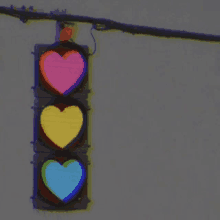 a traffic light with three hearts on it hanging from a pole