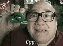 a man with glasses is holding a green egg that says patty 's putts on it