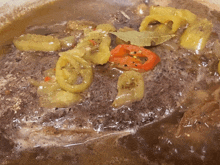 a close up of a pot of stew with peppers and bay leaves