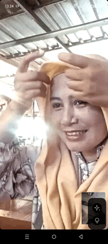 a woman wearing a yellow scarf is smiling and making a heart with her hands