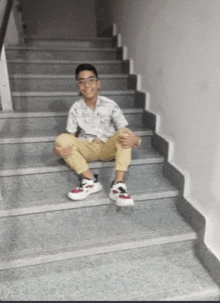 a young boy is sitting on a set of stairs and smiling for the camera .