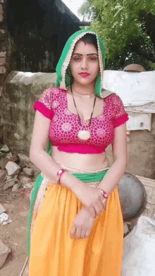 a woman in a pink crop top and yellow skirt stands in front of a building