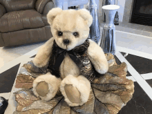 a teddy bear wearing a vest and a black bow sits on a table