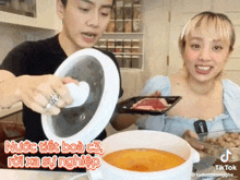 a woman is holding a tray of meat and a man is holding a pot of soup with a caption that says tik tok