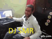 a man in a white shirt is sitting in front of a computer with the words dj smr written on the screen