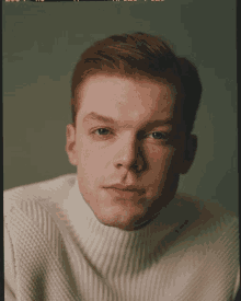 a man with red hair and freckles wearing a white turtleneck sweater