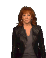 a woman with red hair is wearing a black jacket