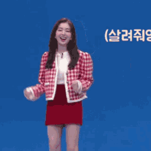 a woman in a red skirt is dancing in front of a blue background with chinese writing on it